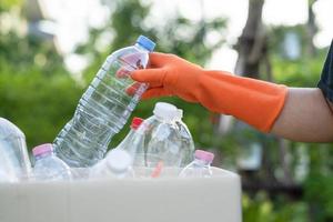une femme asiatique bénévole transporte des bouteilles d'eau en plastique dans la poubelle du parc, recycle le concept d'écologie de l'environnement des déchets. photo