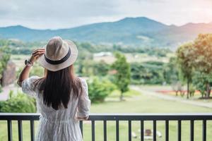 femme heureuse en robe blanche et chapeau à la recherche d'une belle vue sur la nature. concept de détente, de voyage, de nature, de vacances et de vacances