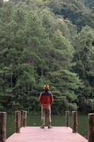 heureux voyageur homme debout et regardant la vue sur la nature, touriste solo en pull voyageant à pang oung, mae hong son, thaïlande. concept de voyage, voyage et vacances photo