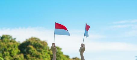 main tenant le drapeau indonésien sur fond de ciel bleu. fête de l'indépendance de l'indonésie, fête nationale et concepts de célébration heureuse photo