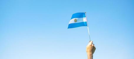 main tenant le drapeau argentin sur fond de nature. 9 juillet du jour de l'indépendance, 25 mai du jour de la révolution et concepts de célébration heureuse photo