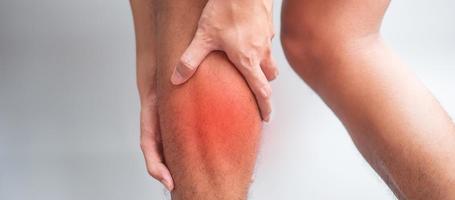 mâle adulte avec ses douleurs musculaires sur fond gris. homme âgé ayant mal à la jambe en raison de la traction musculaire du mollet. blessures sportives et concept médical photo