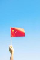 main tenant le drapeau de la chine sur fond de ciel bleu. fête nationale de la république populaire de chine, jour férié de la nation publique et concepts de célébration heureuse photo