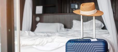 bagages bleus avec chapeau dans une chambre d'hôtel moderne après l'ouverture de la porte. temps de voyager, service, voyage, voyage, vacances d'été et concepts de vacances