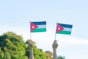 main tenant le drapeau jordanien sur fond de nature. jour de l'indépendance de la jordanie et concepts de célébration heureuse photo