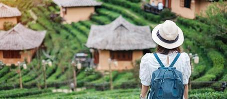 femme touristique heureuse en robe blanche profitez d'un beau jardin de thé.voyageur visitant le village de ban rak thai, mae hong son, thaïlande. concept de voyage, de vacances et de vacances photo