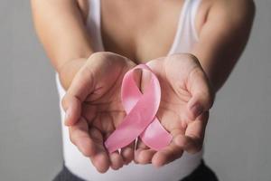 mains de femme tenant des rubans roses pour la sensibilisation au cancer du sein, cancer du sein. concept de soins de santé et de médecine. photo