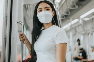 femme asiatique portant un masque de protection dans un train. femme portant un masque de protection chirurgical dans les transports en commun. nouveau concept normal. photo