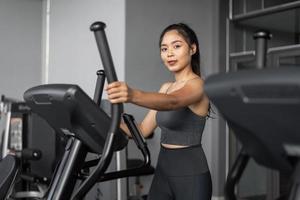 femme asiatique exerce en fitness. jeune femme en bonne santé en vêtements de sport est des exercices cardio en salle de gym. photo