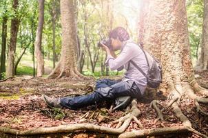 photographe prenant des photos assis sous un grand arbre