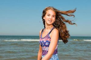 fille heureuse aux longs cheveux bruns profitant de la plage rafraîchissante. photo