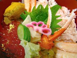 gros plan couleur vibrante de fraîcheur œufs de saumon, œufs d'oursin, garniture de chair de crabe sur riz japonais sashimi don avec concombre gingembre et wasabi photo
