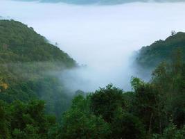 paysage de la montagne couverte de brume le matin avec des rayons de soleil réchauffés pour fond d'écran photo