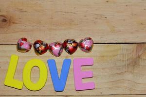 lettres d'amour et coeur en chocolat sur le parquet. fond saint valentin avec des coeurs. concept de la Saint-Valentin. espace pour le texte. photo