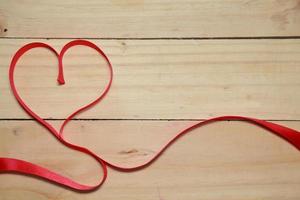 concevoir la sensibilisation du ruban en forme de coeur rouge sur le vieux fond de bois vieilli. concept de la Saint-Valentin. espace pour le texte. photo