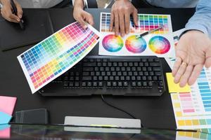 équipe de graphistes travaillant sur la conception de sites Web à l'aide d'échantillons de couleurs éditant des illustrations à l'aide d'une tablette et d'un stylet à des bureaux dans un bureau créatif