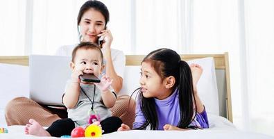 mère indépendante occupée travaillant sur un ordinateur portable et s'occupant de son bébé et de sa petite fille photo