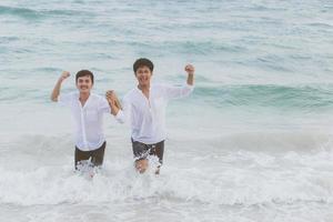 portrait homosexuel jeune couple asiatique courant avec gai ensemble sur la plage en été, asie gay faisant du tourisme pour les loisirs et se détendre avec bonheur en vacances en mer, concept juridique lgbt. photo