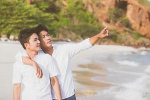 portrait homosexuel jeune couple asiatique debout pointant quelque chose ensemble sur la plage en été, asie gay allant en mer pour les loisirs avec romantique et heureux en vacances en mer, lgbt avec concept juridique. photo