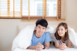 beau portrait jeune couple asiatique se détendre et satisfait ensemble dans la chambre à la maison, famille allongée sur le lit confiant avec gaie et heureuse avec relation, homme et femme datant. photo