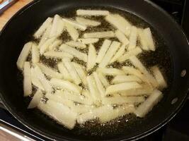 frites de pommes de terre cuisson dans l'huile chaude dans la poêle photo