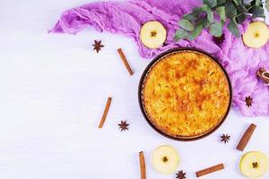 délicieuse tarte aux pommes maison sur fond rose. tarte aux pommes avec des ingrédients, des pommes et de la cannelle. vue de dessus photo