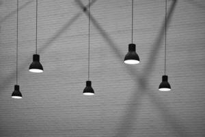 vue latérale et mise au point sélective de 5 lampes suspendues avec lumière et ombre sur la surface du fond de mur de briques dans un style noir et blanc, concept de design d'architecture d'intérieur photo