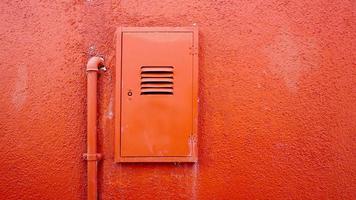 tuyau métallique et boîtier électrique sur mur de couleur orange photo