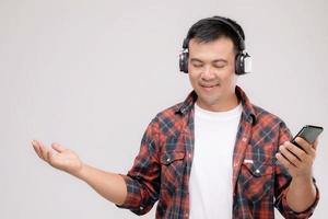 portrait homme asiatique écoutant une chanson ou de la musique à partir d'un casque noir. tourné en studio isolé sur gris photo