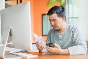 homme tenant et regardant la bouteille de gel désinfectant pour les mains qu'il a commandé d'utiliser à la maison, travail à domicile et concept sain photo