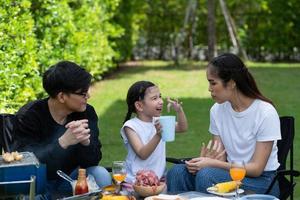 les activités de vacances en famille incluent le père, la mère et les enfants avec un barbecue de camping et jouent dans la cour ensemble joyeusement en vacances. photo