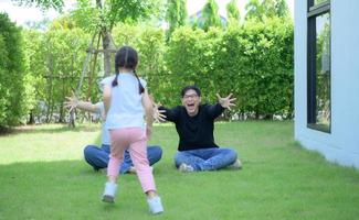 famille asiatique avec père, mère et fille s'amusant joyeusement dans le jardin de la maison photo