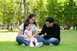 famille asiatique avec père, mère et fille s'amusant joyeusement dans le jardin de la maison photo