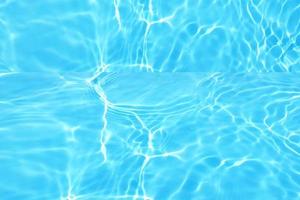 défocalisation de l'eau bleue floue dans la piscine fond de détail de l'eau ridée. surface de l'eau dans la mer, fond de l'océan. l'eau est une substance inorganique, transparente, insipide, inodore et presque incolore. photo