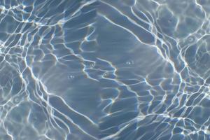 défocalisation de l'eau bleue floue dans la piscine fond de détail de l'eau ridée. surface de l'eau dans la mer, fond de l'océan. l'eau est une substance inorganique, transparente, insipide, inodore et presque incolore. photo