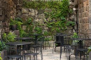 photographie d'été atmosphérique. café en plein air avec chaises et tables noires. café de rue en plein air avec beaucoup de plantes photo