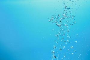 image de fond abstrait de bulles dans l'eau. eau propre avec des gouttelettes d'eau et des vagues. eau douce un verre avec fond bleu bulles. photo