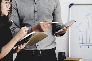 un expert en investissement pointe un stylo sur un moniteur de tablette pour analyser le marché boursier et vous apprendre à réaliser un profit. photo