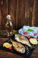poisson dorado grillé sur fond en bois. poisson de mer rôti aux épices et herbes photo