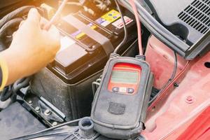 le mécanicien automobile utilise un voltmètre pour vérifier le niveau de tension de la batterie de la voiture photo