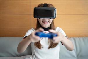 gros plan femme asiatique heureuse émotion jouant à des jeux vidéo avec contrôleur sur fond abstrait tonique avec des lunettes virtuelles photo