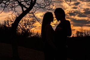 silhouette de couple romantique amoureux, homme et femme dans le ciel coucher de soleil. romantique des relations entre couple amour dans le jardin photo