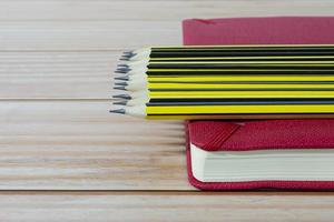 crayons en bois 2b allongés sur un carnet de notes rouge sur une table en bois. espace de copie. photo