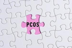 texte pcos sur puzzle blanc sur fond rose. notion de soins de santé. photo