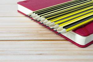 crayons en bois 2b allongés sur un carnet de notes rouge sur une table en bois. espace de copie. photo