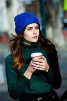 jeune femme élégante buvant du thé dans une rue de la ville. fille européenne hipster avec verre de papier latte. magnifique jeune femme avec une tasse de café dans la rue de la ville. pause café. café à emporter.