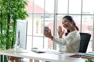 travail à domicile et concept d'apprentissage en ligne. de jolies jeunes femmes travaillant sur ordinateur regardent l'écran à l'aide d'un smartphone dans le salon ou l'espace de co-working. cours de formation en ligne pour étudiants. photo