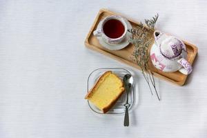 prendre le petit déjeuner avec du thé chinois avec un gâteau moelleux décoré de fleurs séchées au travail depuis l'espace de travail à domicile. photo