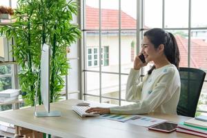 travail à domicile et concept d'apprentissage en ligne. de jolies jeunes femmes travaillant sur ordinateur regardent l'écran à l'aide d'un smartphone dans le salon ou l'espace de co-working. cours de formation en ligne pour étudiants. photo