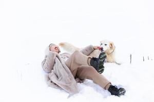 belle jeune femme et son chien golden retriever s'amusant en hiver. photo